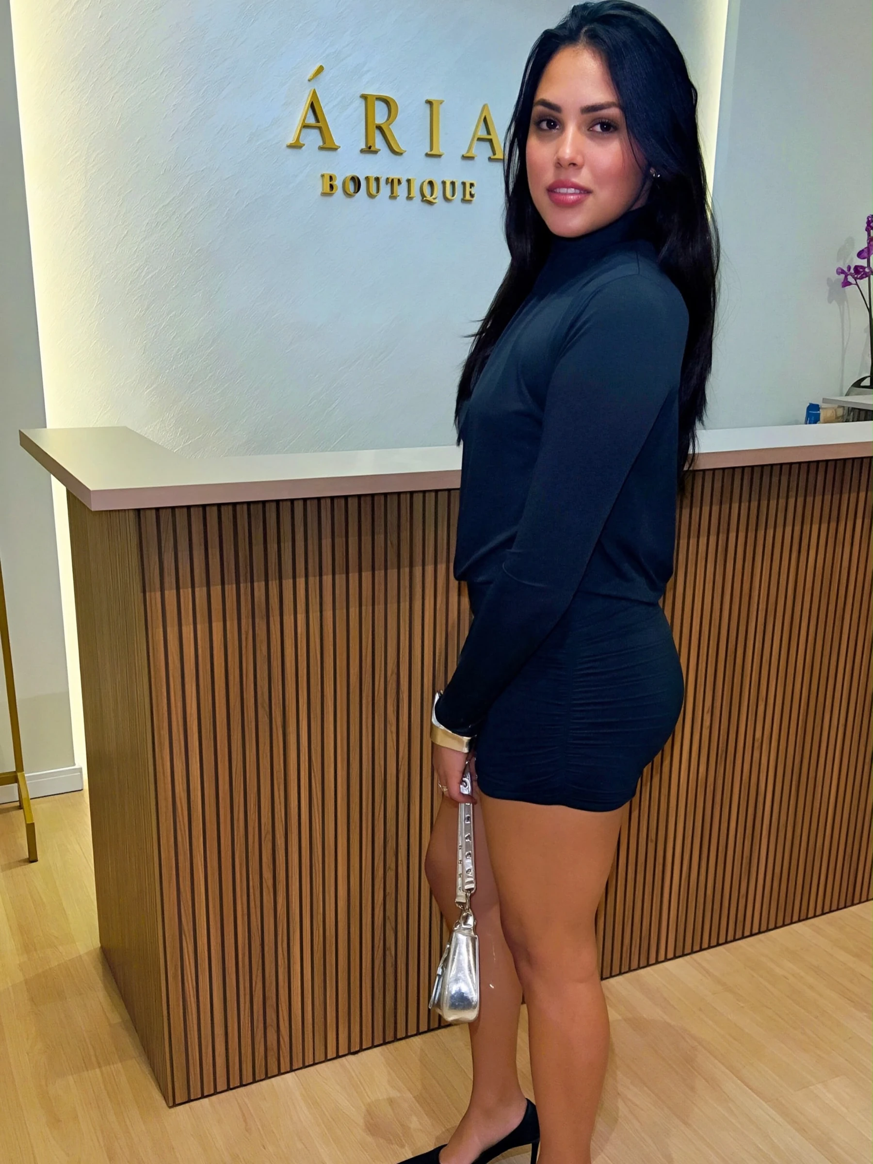 Cliente usa vestido preto diante do balcão da Ária Boutique